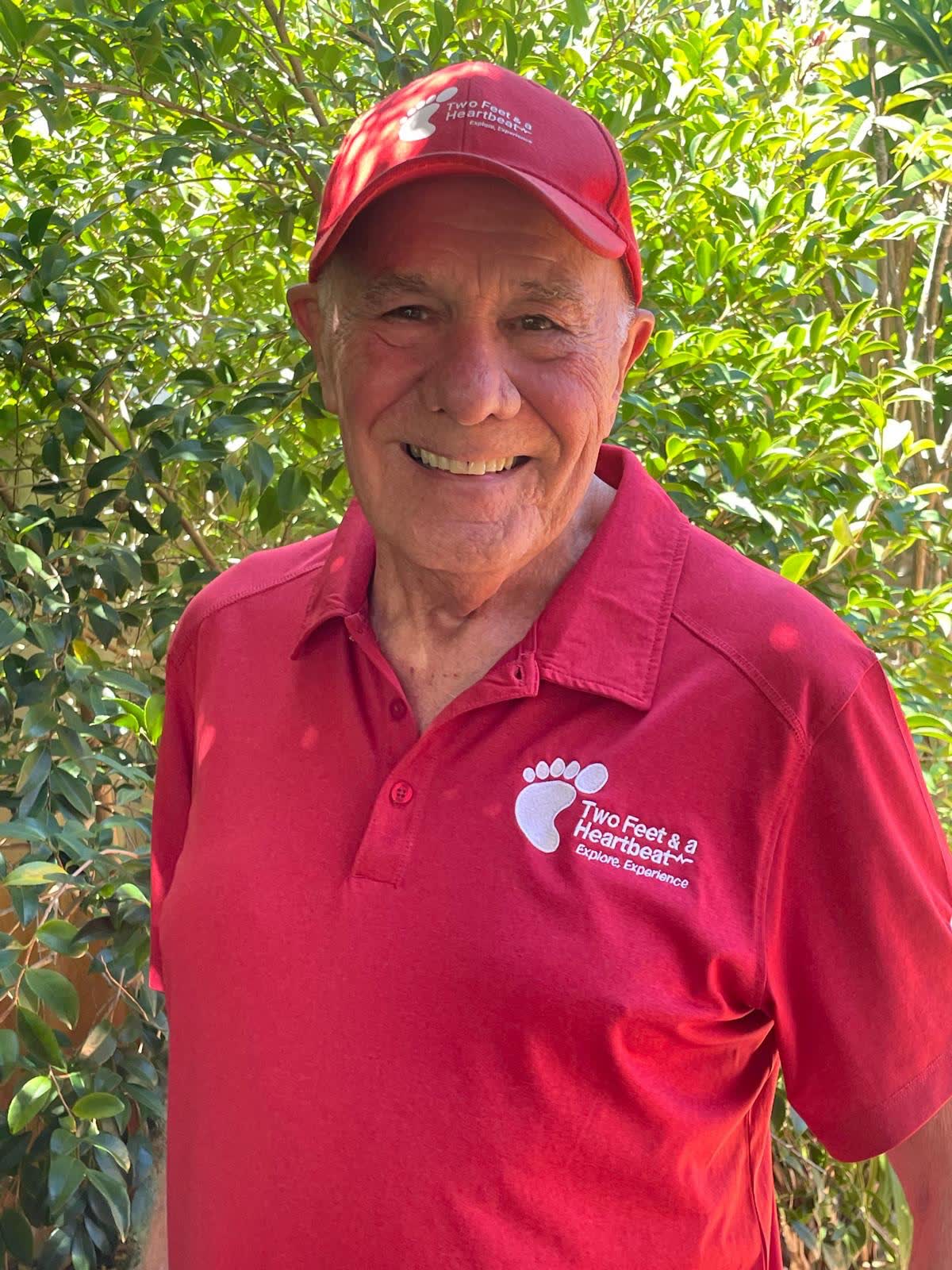 Two Feet guide Vaughan smiling outdoors in his red Two Feet & a Heartbeat polo